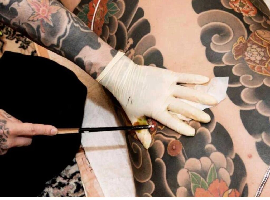 A tattoo artist injects ink using traditional techniques and tools.